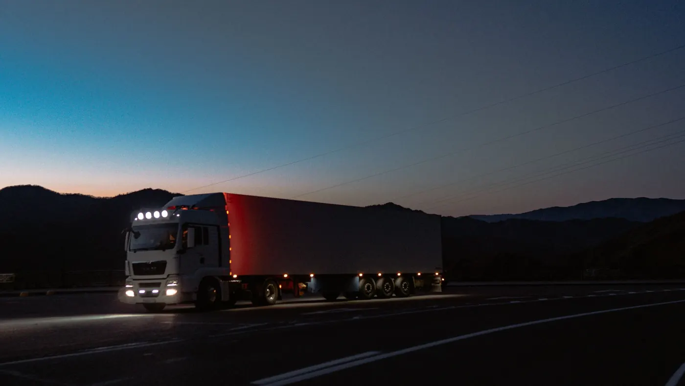 A lorry at dusk with its lights on